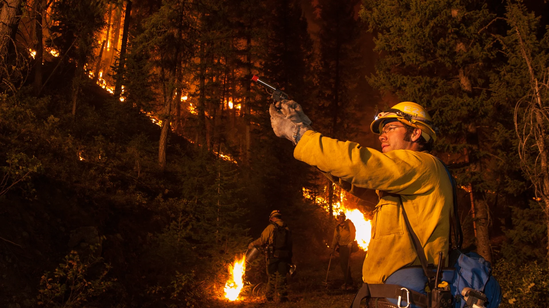 Firefighter battling forest blaze at night